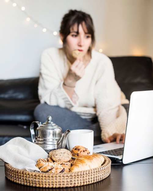 Foto grátis café da manhã na bandeja na frente da mulher usando laptop