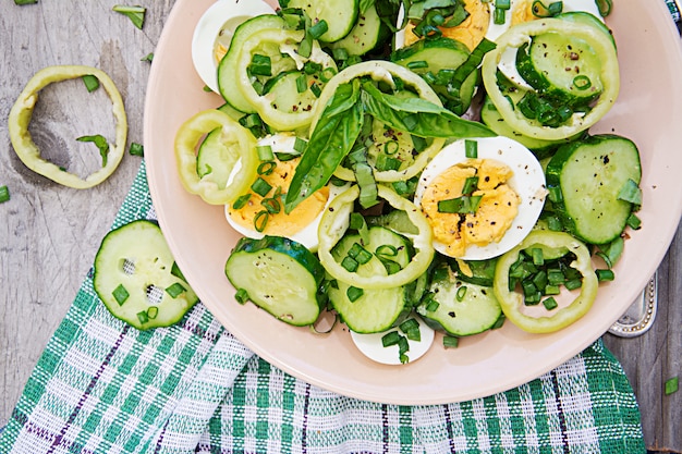 Café da manhã no jardim de verão. Salada de ovos e pepinos com cebolinha e manjericão. Vista do topo. Configuração plana