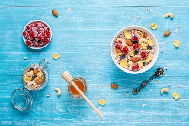 Café da manhã saudável. Granola fresca, muesli com nozes e frutas congeladas. Vista do topo. Copie o espaço.