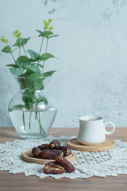 Café de aroma e deliciosas tâmaras na mesa de madeira.