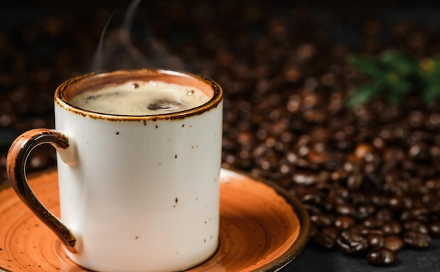 Café expresso com espuma perfumada em uma xícara em grãos de café de fundo preto ao fundo