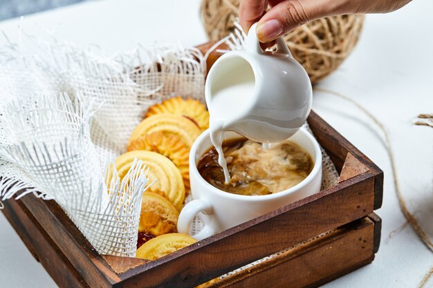 Café, leite e um prato de biscoitos.