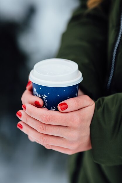 Café nas mãos. As mãos das mulheres detém café quente nas mãos ao ar livre no dia frio de inverno