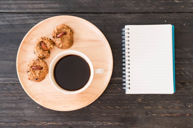 Café preto e biscoitos com laptop e livro de notas