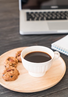 Café preto e biscoitos com laptop e livro de notas