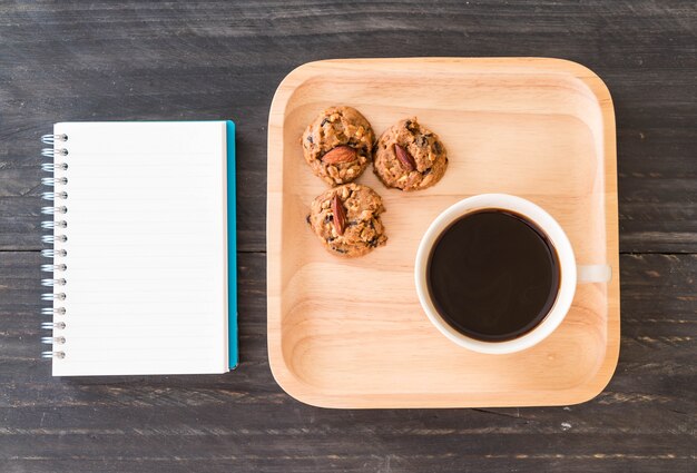 Café preto e biscoitos com laptop e livro de notas