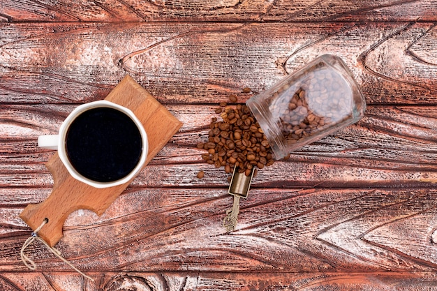 café preto na placa de madeira com pote de grãos de café vista superior