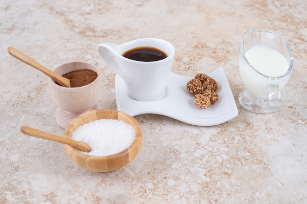 Café preto, tigelas de pó de café moído e açúcar e amendoim glaceado