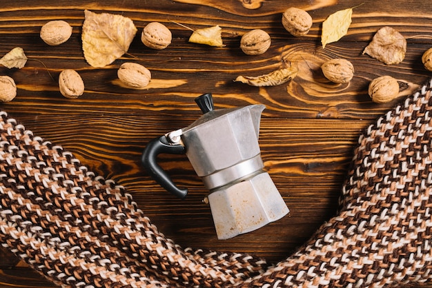 Foto grátis cafeteira e cachecol perto de nozes e folhas