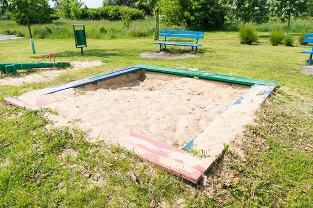 Caixa de areia com areia branca em um playground gramado