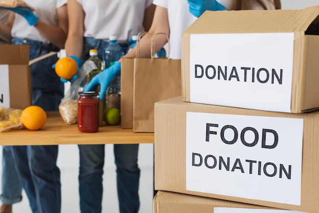 Foto grátis caixa de doação de alimentos sendo preparada por voluntários com luvas