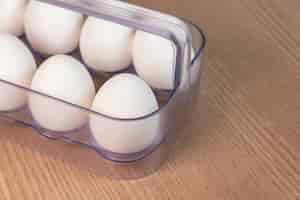 Foto grátis caixa de ovo branco na superfície de madeira marrom