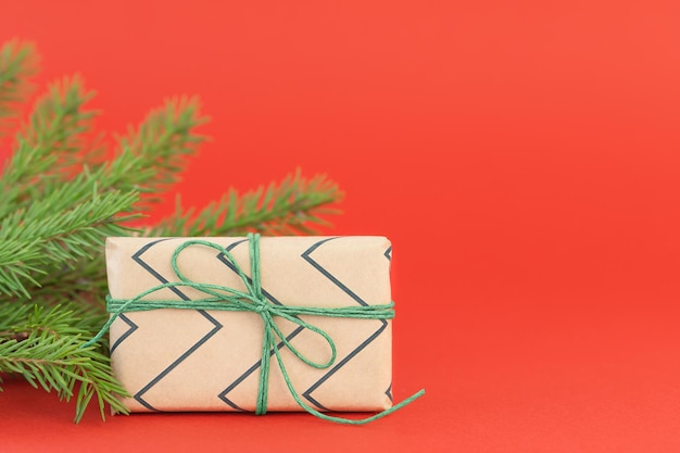 Caixa de presente de natal com ramo de abeto em fundo vermelho