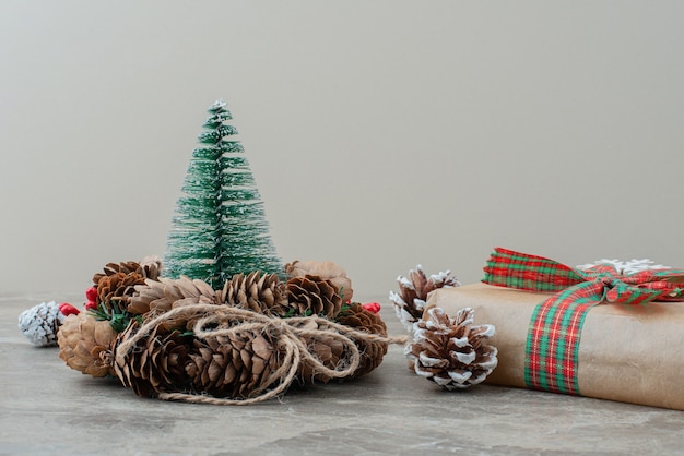 Caixa de presente de natal, pinhas e coroa de flores na mesa de mármore.