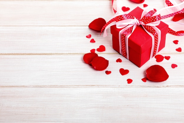 caixa de presente do Valentim e pétalas de rosa na placa de madeira branca