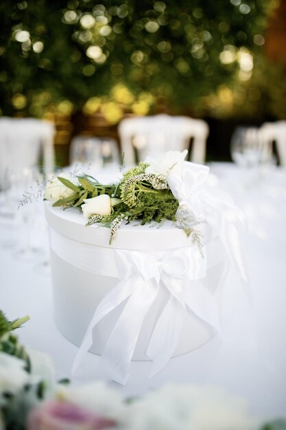 Caixa de presente elegante com rosas brancas na mesa de casamento.