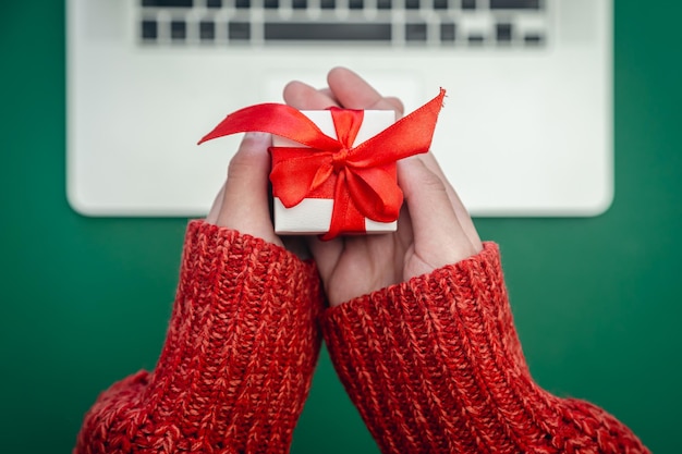 Caixa de presente em mãos femininas e conceito de compras de natal online para laptop