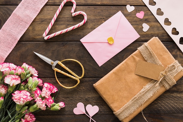 Foto grátis caixa de presente entre flores, envelope e bastões de doces