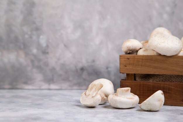 Caixa velha de madeira com cogumelos champignon inteiros frescos isolados na pedra