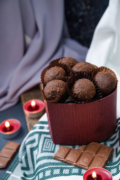 Foto grátis caixa vermelha de chocolates, barra leitosa e velas flamejantes na toalha da mesa