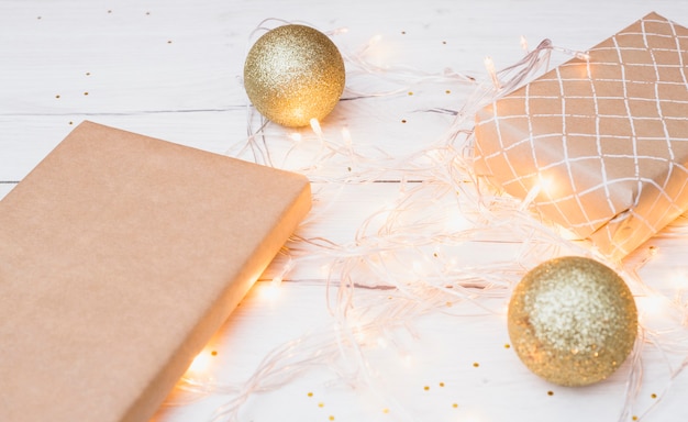 Foto grátis caixas de presente no envoltório e bolas de natal perto de luzes de fadas iluminadas