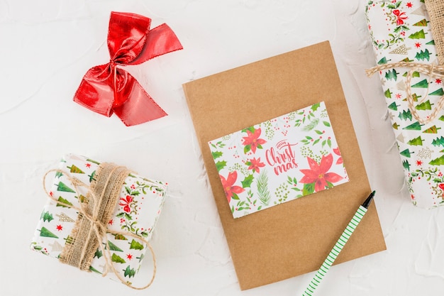 Caixas de presentes entre tablet, caneta, arco e cartão postal