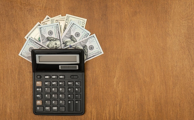 Foto grátis calculadora e notas de dólar em uma configuração plana de fundo de madeira
