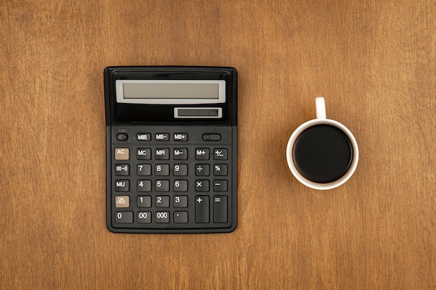 Calculadora e uma xícara de café em um fundo de madeira