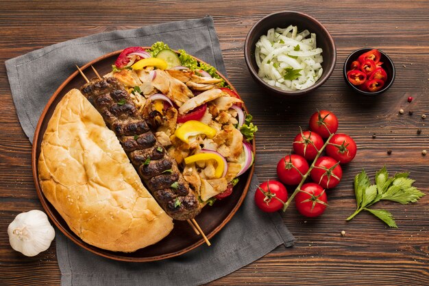 Camada plana de variedade de kebab saboroso com tomate e ervas