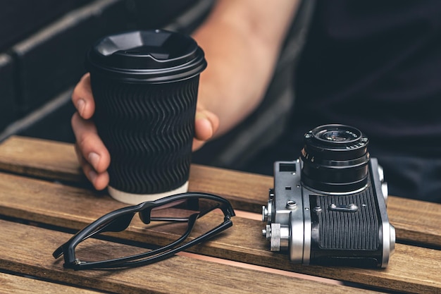 Câmera de filme vintage e um copo de café em uma mesa de madeira