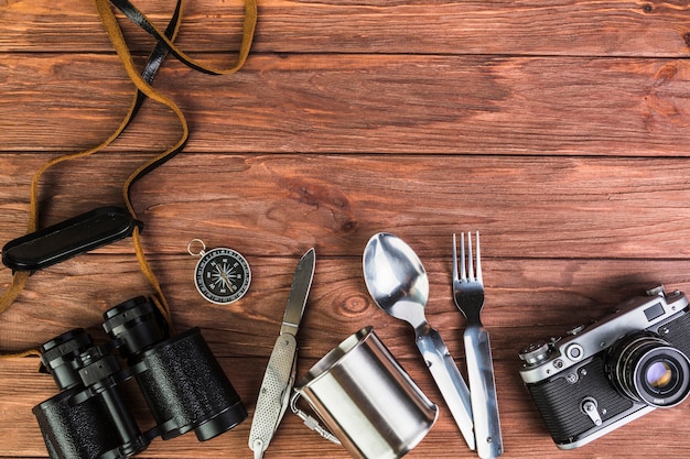 Câmera e binóculo com utensílios de cozinha na mesa de madeira