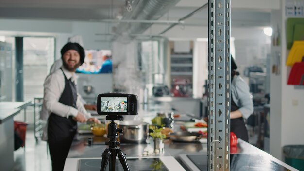 Câmera profissional gravando conteúdo de programas de culinária com chefs na cozinha do restaurante, filmando pessoas fazendo pratos de receita de comida com ingredientes frescos. Aula online de gastronomia.