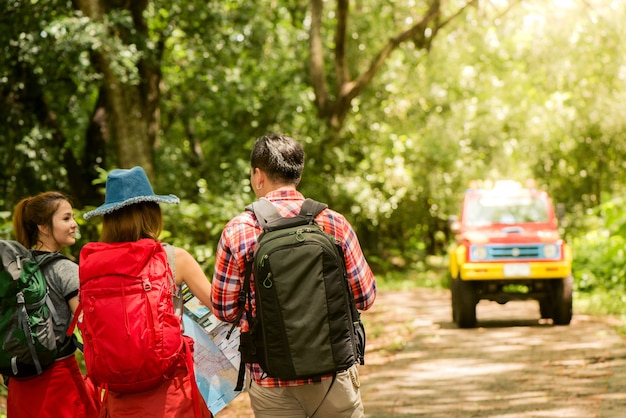 Caminhadas - caminhantes olhando para o mapa. Casal ou amigos navegando juntos, sorrindo feliz durante a viagem de acampamento, caminhar ao ar livre na floresta. Jovem raça asiática mulher e homem.