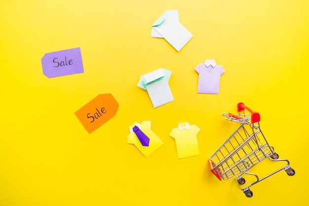 Camisas de papel de brinquedo brilhante perto de carrinho de compras e venda tags