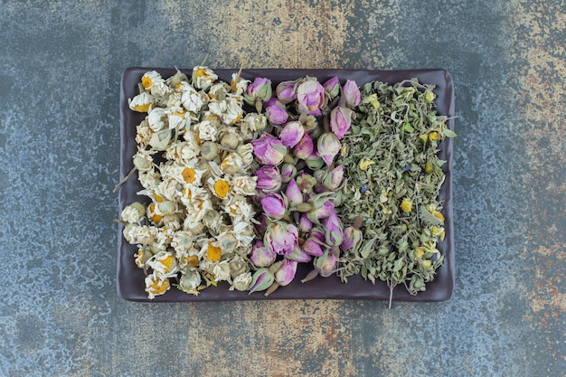 Camomila seca, rosa e folhas na chapa escura.