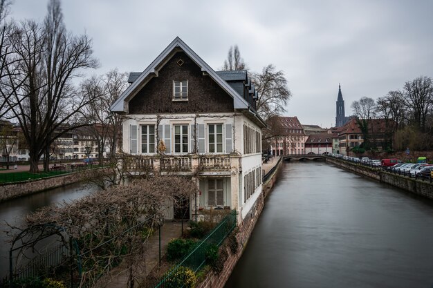 Canal cercado por edifícios e vegetação sob um céu nublado em Estrasburgo, na França