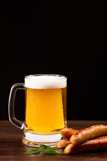 Caneca de cerveja e salsichas na placa de madeira