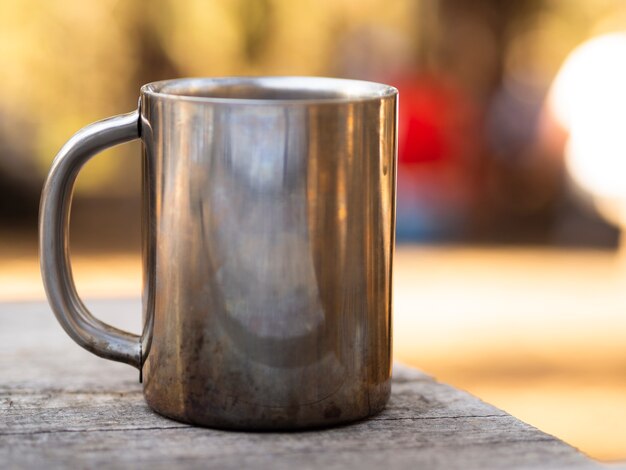 Caneca de metal com brilho na mesa de madeira gasto