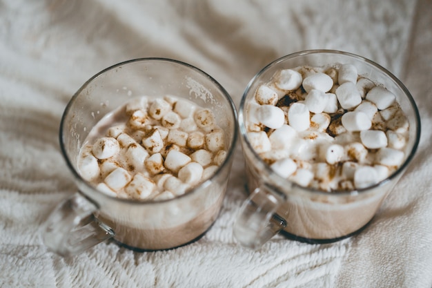 canecas de cacau com marshmallows perto da lareira.