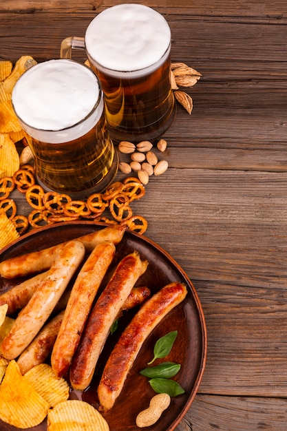 Foto grátis canecas de cerveja e prato com salsichas