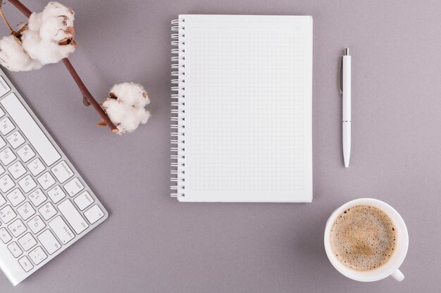 Foto grátis caneta perto de bloco de notas, teclado, galho e copo