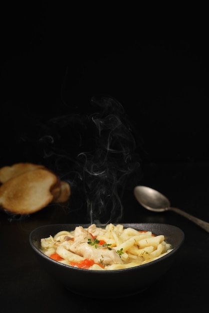 Foto grátis canja de galinha com legumes, especiarias e macarrão caseiro em uma mesa escura.