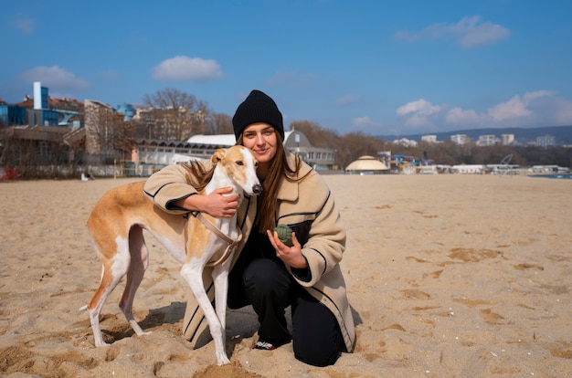 Foto grátis cão galgo com dona na praia