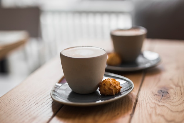 Cappuccino ou latte com espuma espumante com cookie na mesa de madeira