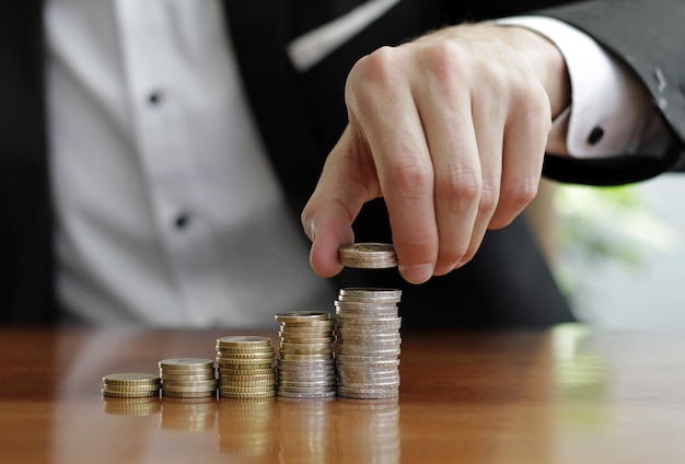 Captura aproximada das mãos de um empresário contando pilhas de moedas após o sucesso do negócio