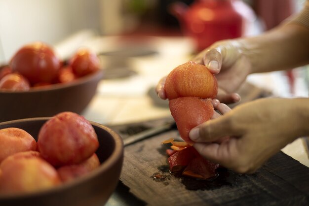 Captura aproximada de uma fêmea descascando um tomate com fundo desfocado