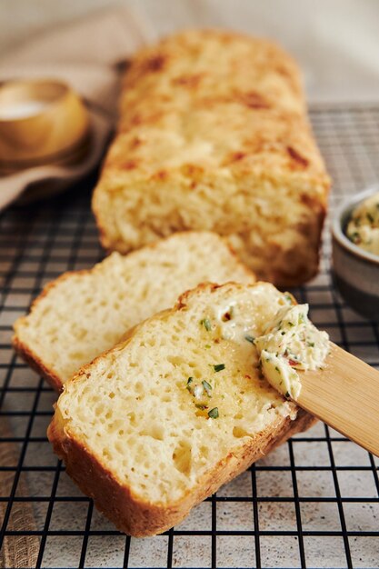 Captura de um delicioso pão de queijo com manteiga de ervas em uma mesa branca