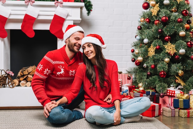 Cara abraçando a senhora perto de árvore de Natal