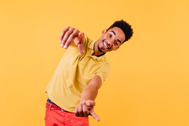 Cara africano emocional olhando com um sorriso. Que bom garoto negro bem vestido expressando felicidade.