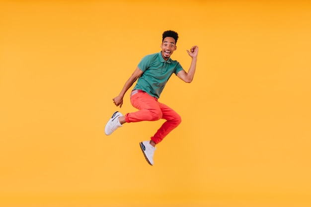 Cara alegre de cabelos curtos pulando. Foto interna da deslumbrante modelo masculino em t-shirt verde se divertindo.